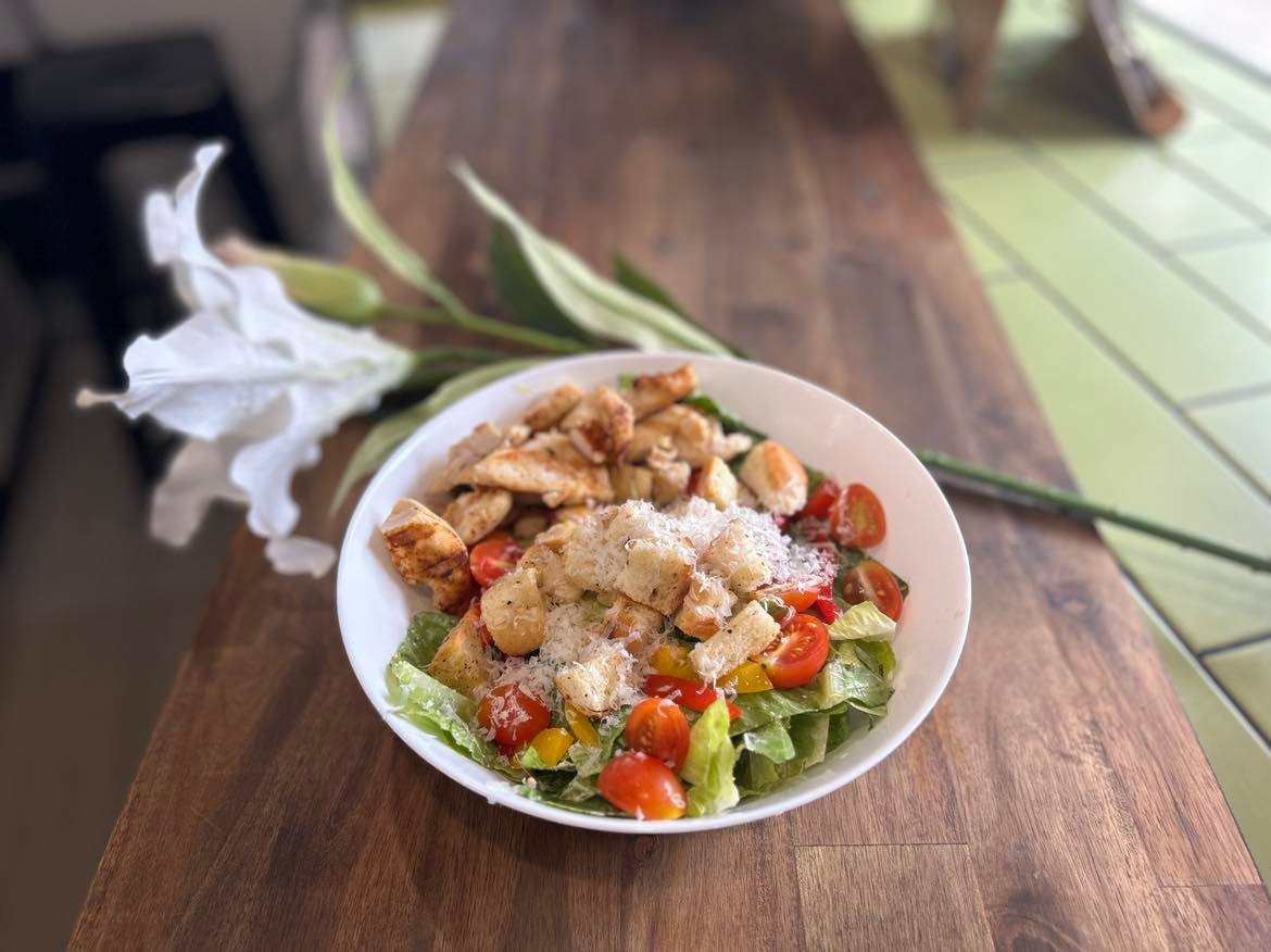 A grilled chicken salad bowl on a timber bench