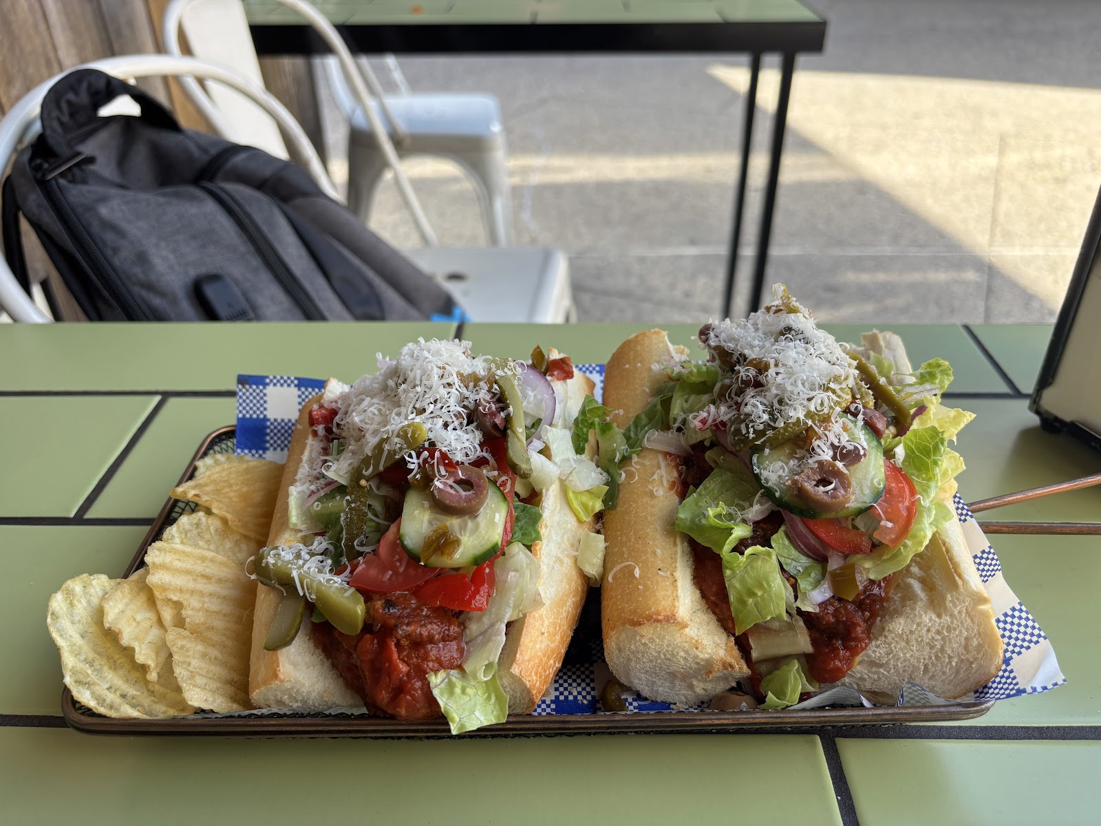 Two loaded subs topped with parmesan, served with chips