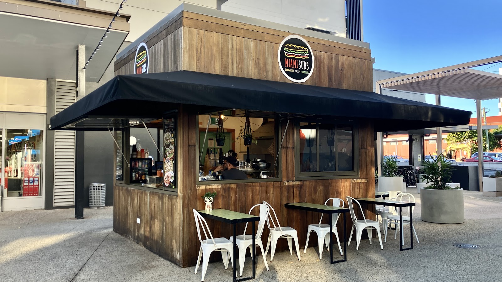 The Miami Subs kiosk with white bistro chairs and tables out front