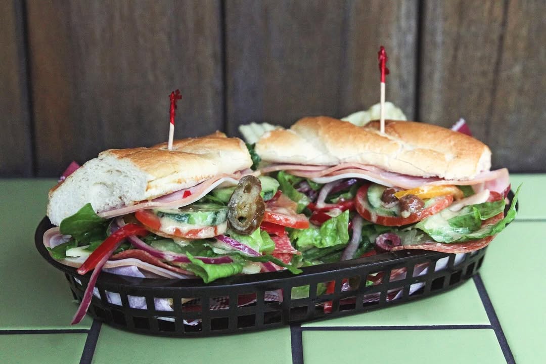 A deli sub piled with salad in a basket